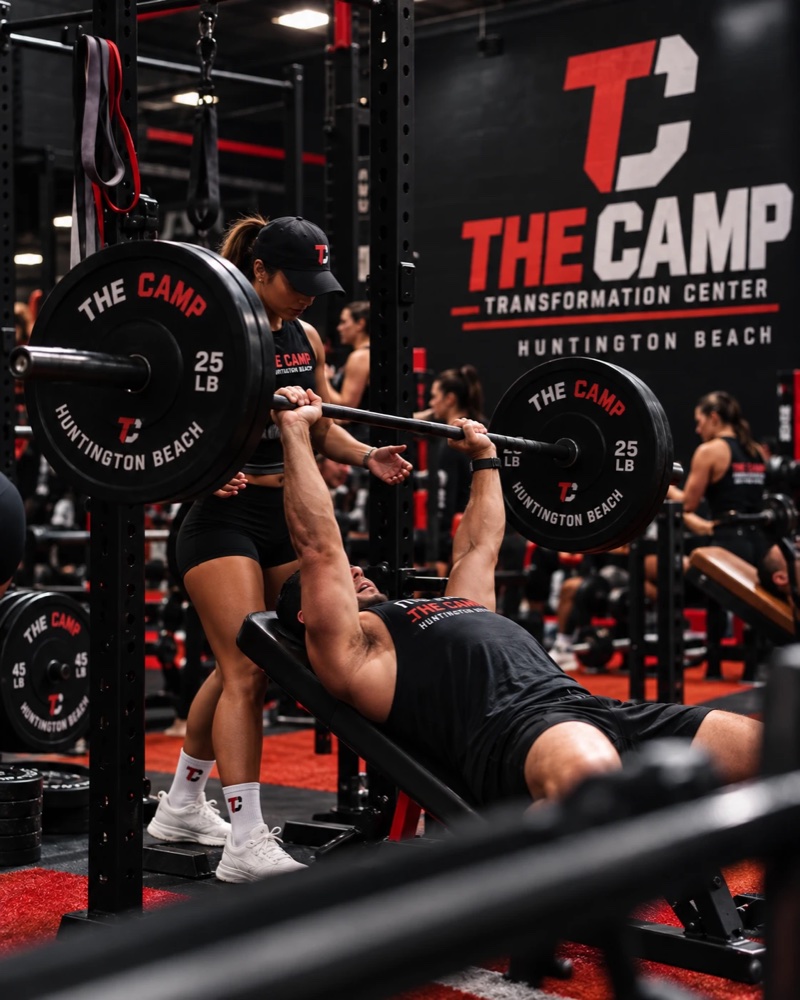 A coach spotting a member through a barbell bench press.